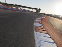 a view of an outdoor stadium racing track and bridge during the day of daylight with one runner on the side