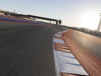 a view of an outdoor stadium racing track and bridge during the day of daylight with one runner on the side