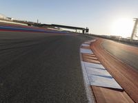 a view of an outdoor stadium racing track and bridge during the day of daylight with one runner on the side