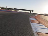 a view of an outdoor stadium racing track and bridge during the day of daylight with one runner on the side