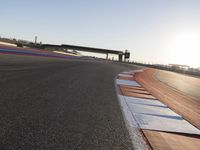 a view of an outdoor stadium racing track and bridge during the day of daylight with one runner on the side