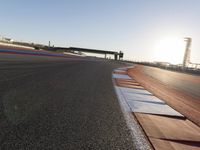 a view of an outdoor stadium racing track and bridge during the day of daylight with one runner on the side