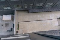 an overhead view of a large building with concrete steps in front and a building that has several windows