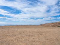 a person stands on the side of a mountain near a hilltop looking over a barren landscape