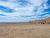 a person stands on the side of a mountain near a hilltop looking over a barren landscape