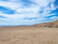 a person stands on the side of a mountain near a hilltop looking over a barren landscape