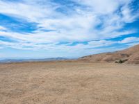 a person stands on the side of a mountain near a hilltop looking over a barren landscape