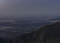 a view of a mountain valley with many mountains in the distance, a bird flies above