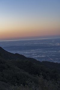 a view of a mountain valley with many mountains in the distance, a bird flies above