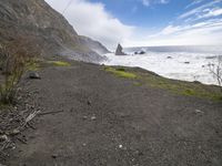 the cliff side with small rocks that is in the distance and a person sitting on top of a surfboard