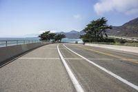 a paved roadway on a mountain side overlooking the ocean with a car driving near by