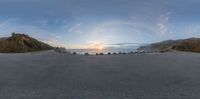 a road going to the beach at sunset with view in a fish eye lens with mountain in the distance