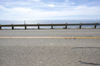 a long bench is sitting in the middle of a highway with ocean in the background