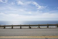 a long bench is sitting in the middle of a highway with ocean in the background