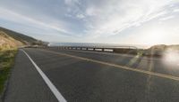 a large long highway with a ocean and mountain on the back side of it on a clear day