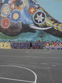 a painted elephant is pictured in front of a building with a wall on it's side