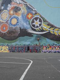 a painted elephant is pictured in front of a building with a wall on it's side