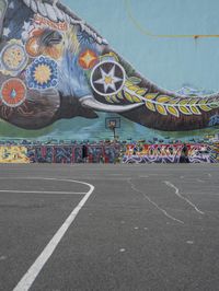 a painted elephant is pictured in front of a building with a wall on it's side