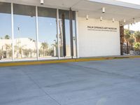 a building with a sidewalk next to it on a sunny day, showing the entrance