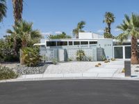 a large house with palm trees in front of it and white doors that open onto a gravel driveway