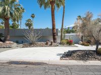 a desert home is shown with many shrubs in the front yard and a street corner