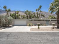 the exterior of a home in palm springs with a garage surrounded by trees and bushes