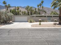 the exterior of a home in palm springs with a garage surrounded by trees and bushes