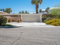 this white home is located with several palm trees and landscaping around it, along the curb