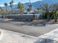 an empty driveway in front of mountains, palm trees and other architecture features throughout the space