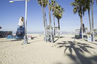 palm trees and a fence with graffiti written on it next to the beach on a sunny day
