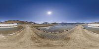 a panorama with a full moon over some small body of water on some rocky ground