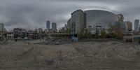 this is a panorama of a wide open space with buildings in the background on a cloudy day