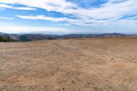 desert area with sparse brown ground and blue sky in background with clouds and mountain views