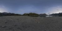 panoramic of a lake in the mountains with water and clouds above it at dusk