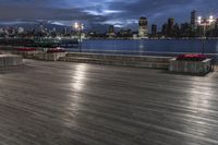 a view of new york city skyline at night from pier on the hudson river side