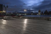 a view of new york city skyline at night from pier on the hudson river side
