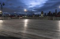 a view of new york city skyline at night from pier on the hudson river side