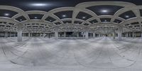 a panoramic view of a parking garage with columns and arches at night with a red fire hydrant