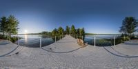 the panoramic lens shows the pathway through the sand with trees in the background