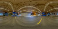 the image shows a panoramic photo of an empty train station area with a few cars parked