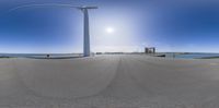 an 360 - view of the beach is seen here in this fish eye photograph that shows the sun, a wind turbine and several other types of seafronts