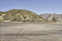 a view along a dirt road of an empty field and mountains in the distance of the scene