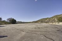 a view along a dirt road of an empty field and mountains in the distance of the scene