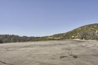 a view along a dirt road of an empty field and mountains in the distance of the scene