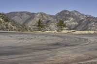 a view along a dirt road of an empty field and mountains in the distance of the scene