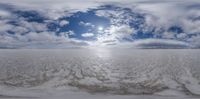 a panoramic view of the surface of the ocean with clouds in the background