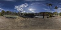 a panorama of an rv parked at a park in the dirt and a man riding a skateboard down the side of a road