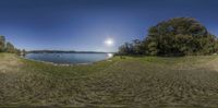 panorama of a small lake by a shoreline under a blue sky with a large white spot