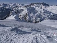 snow covered mountains and hills with a skier standing on the top of the hill, looking down