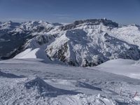 snow covered mountains and hills with a skier standing on the top of the hill, looking down